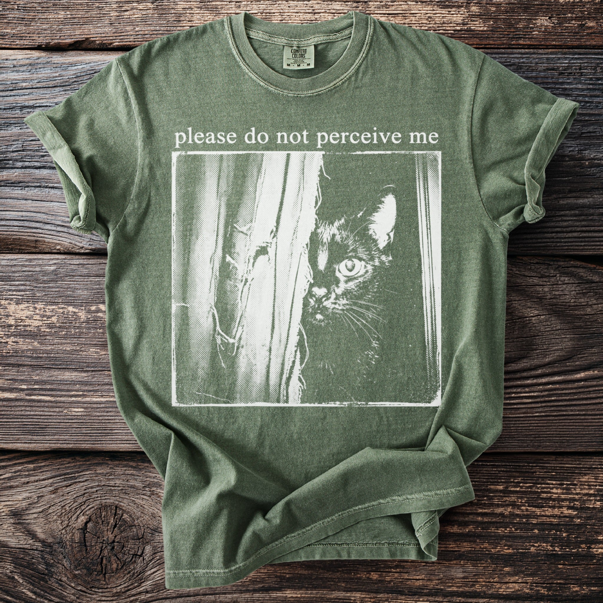 Olive green comfort colors t-shirt with "please do not perceive me" and a black cat graphic.