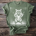 Olive green t-shirt with a distressed white raccoon graphic and "become ungovernable" text.