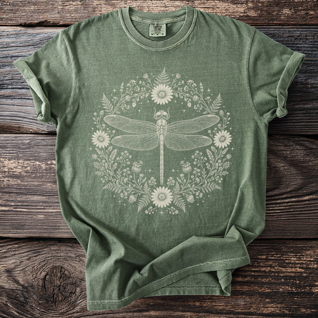Green t-shirt with a white line drawing of a dragonfly in a floral wreath.