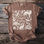 Brown t-shirt with white line art of desert animals and plants and text "respect the locals".