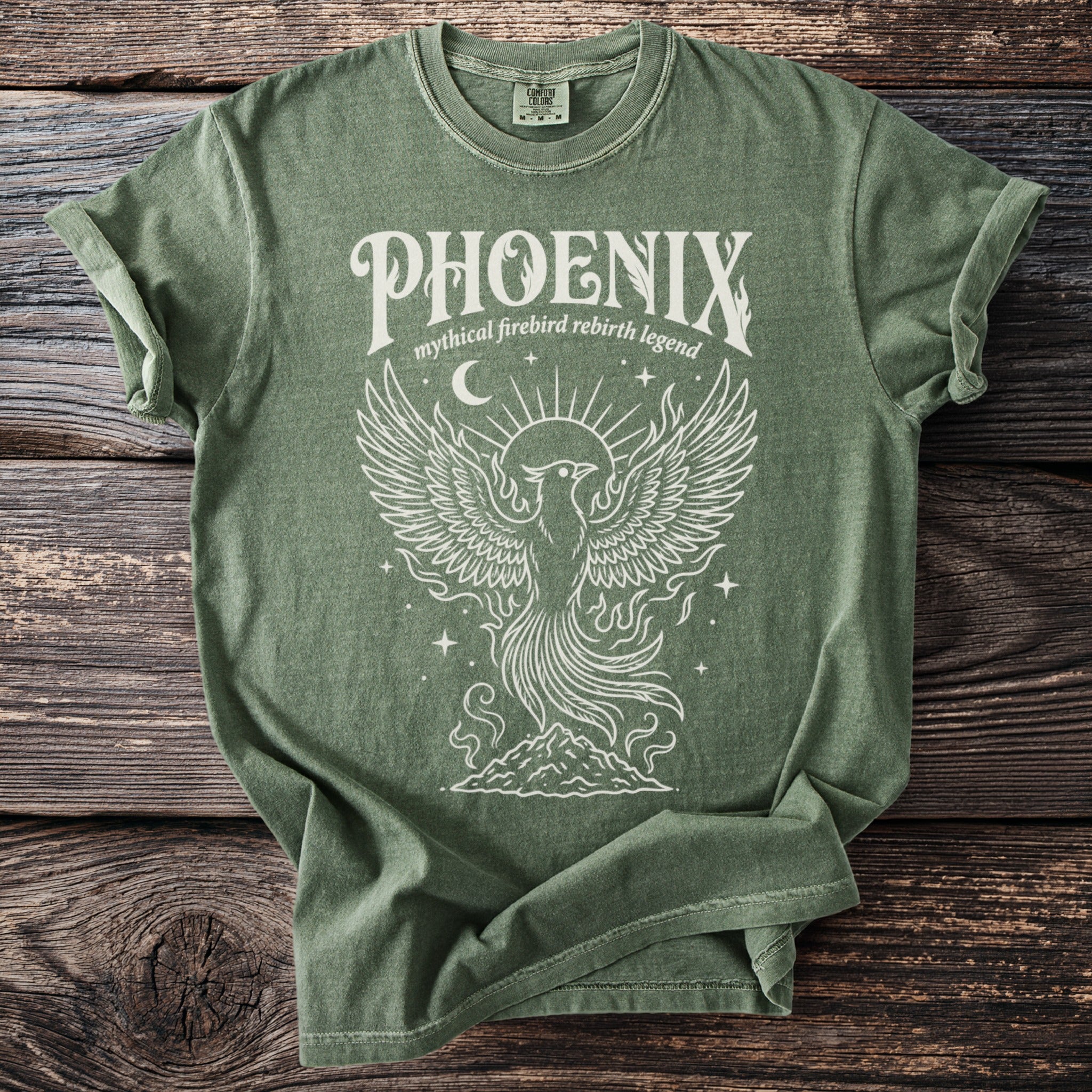Green t-shirt with white line art of a phoenix rising from mountains.