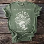 Green t-shirt with skull, plants, mushrooms, book, and text "ALL PLANTS ARE EDIBLE SOME ONLY ONCE".