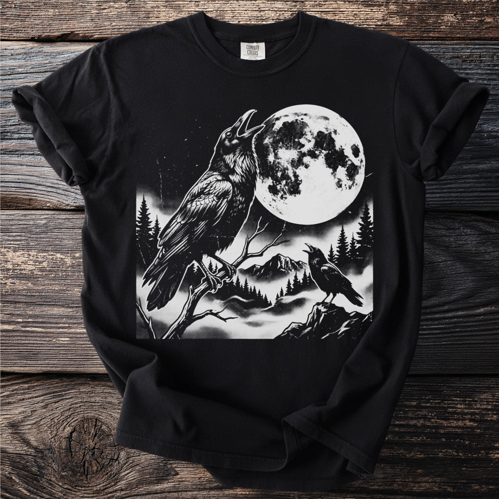 Black t-shirt graphic featuring two ravens, a large moon, and a foggy mountainous landscape.