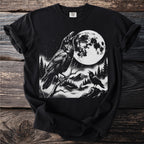 Black t-shirt graphic featuring two ravens, a large moon, and a foggy mountainous landscape.