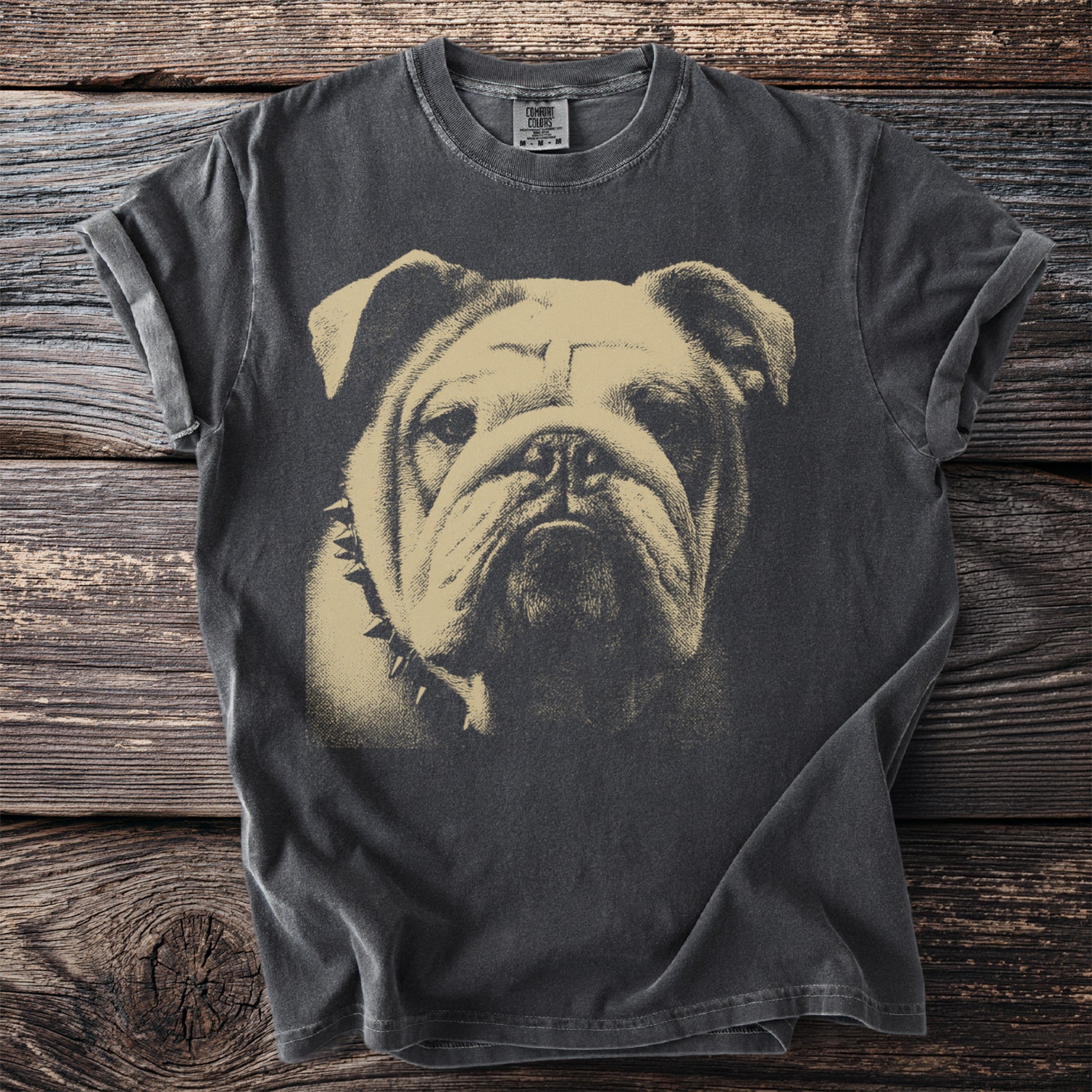 Dark t-shirt with a beige imprint of a bulldog's face wearing a spiked collar.