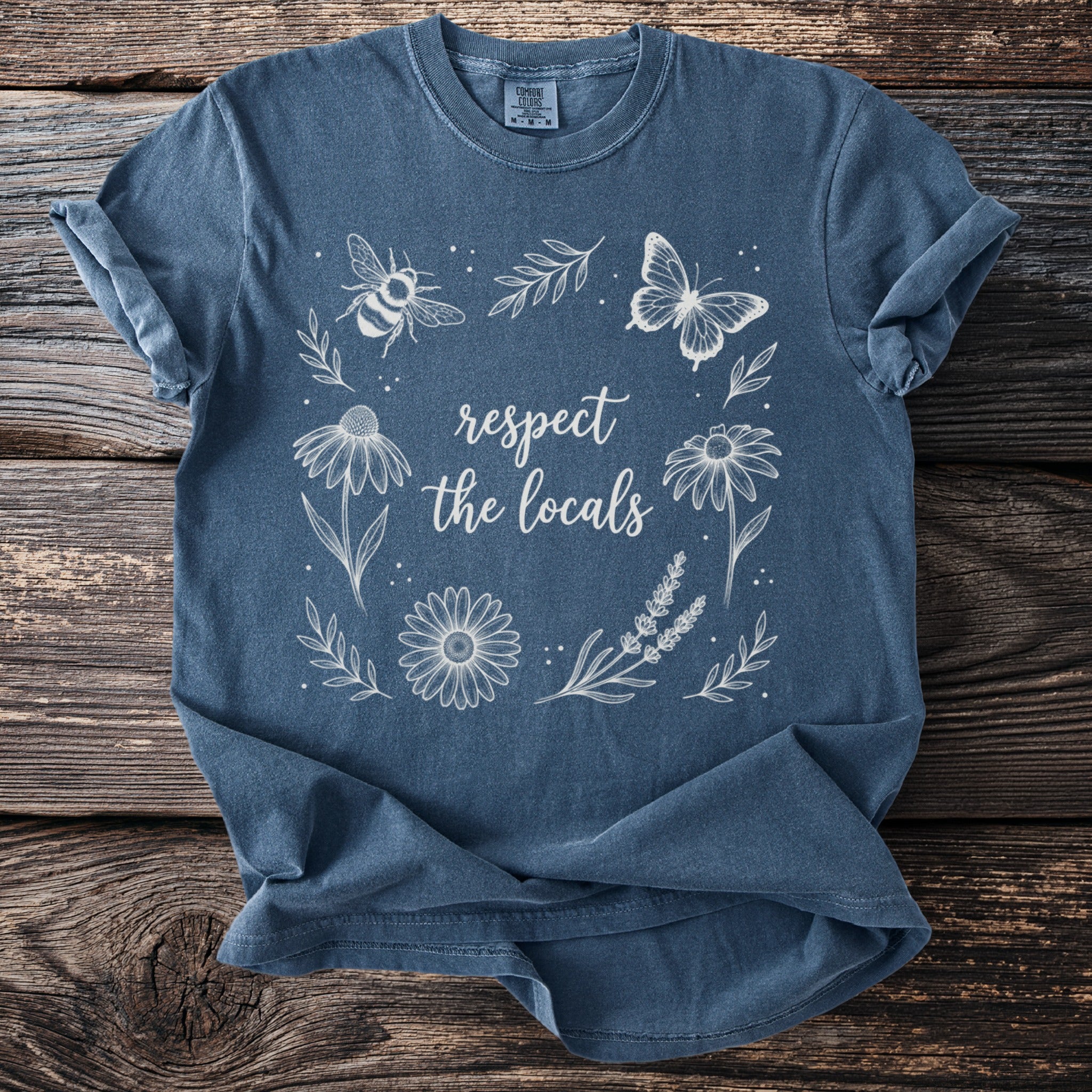 Blue t-shirt with white line art of bee, butterfly, flowers, and text: "respect the locals"