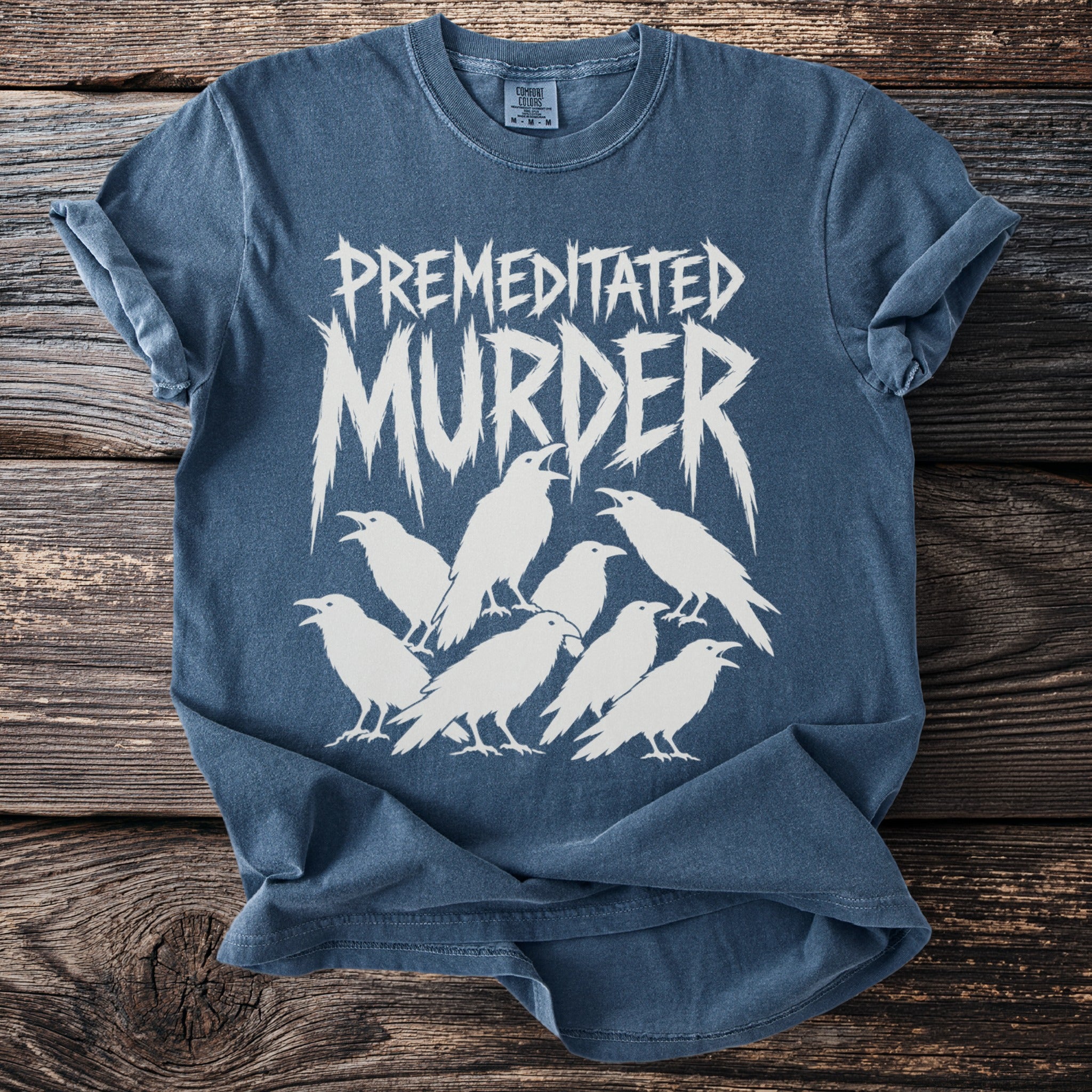 Blue t-shirt with white text "PREMEDITATED MURDER" and white ravens.