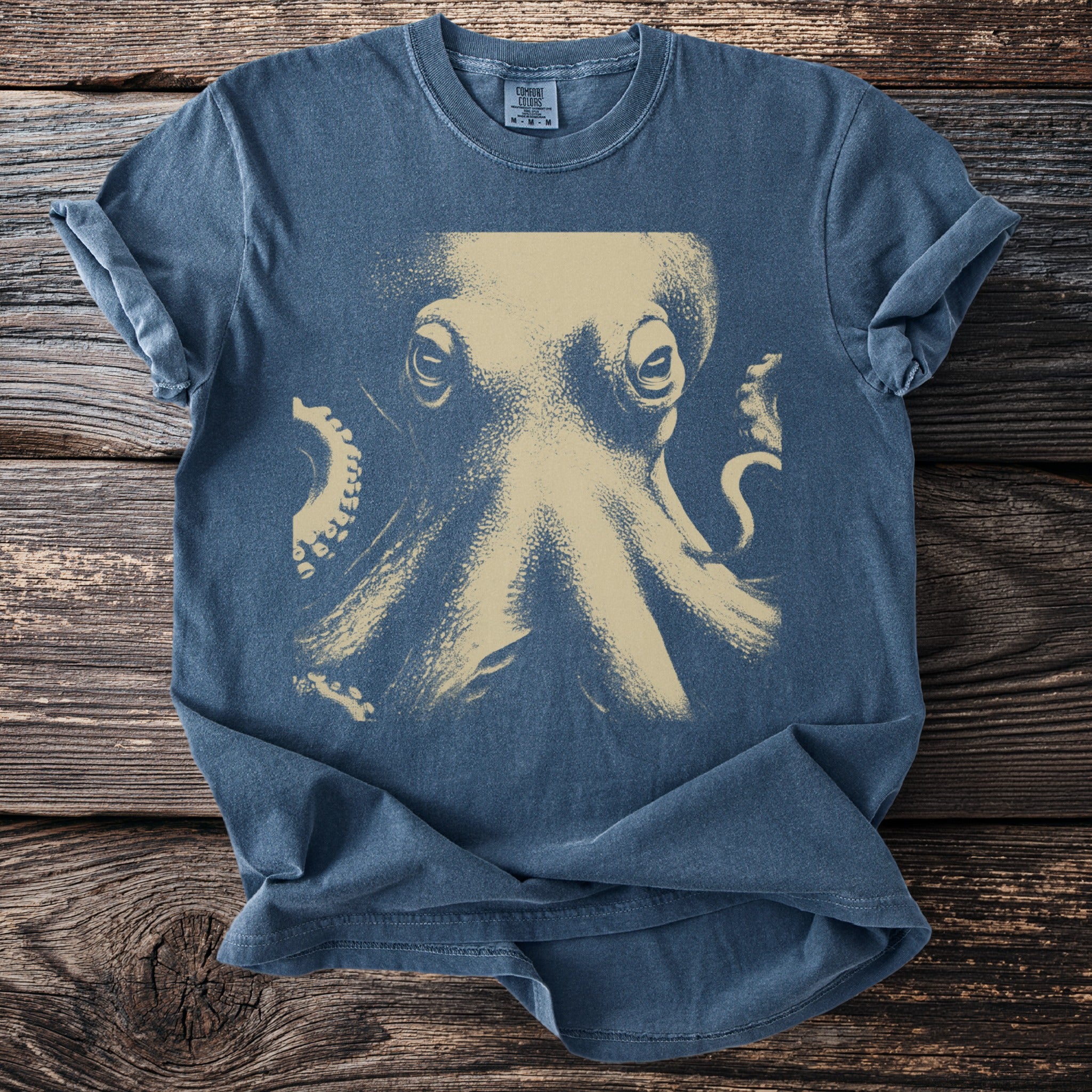 Blue Comfort Colors t-shirt with a faded tan octopus graphic and text.