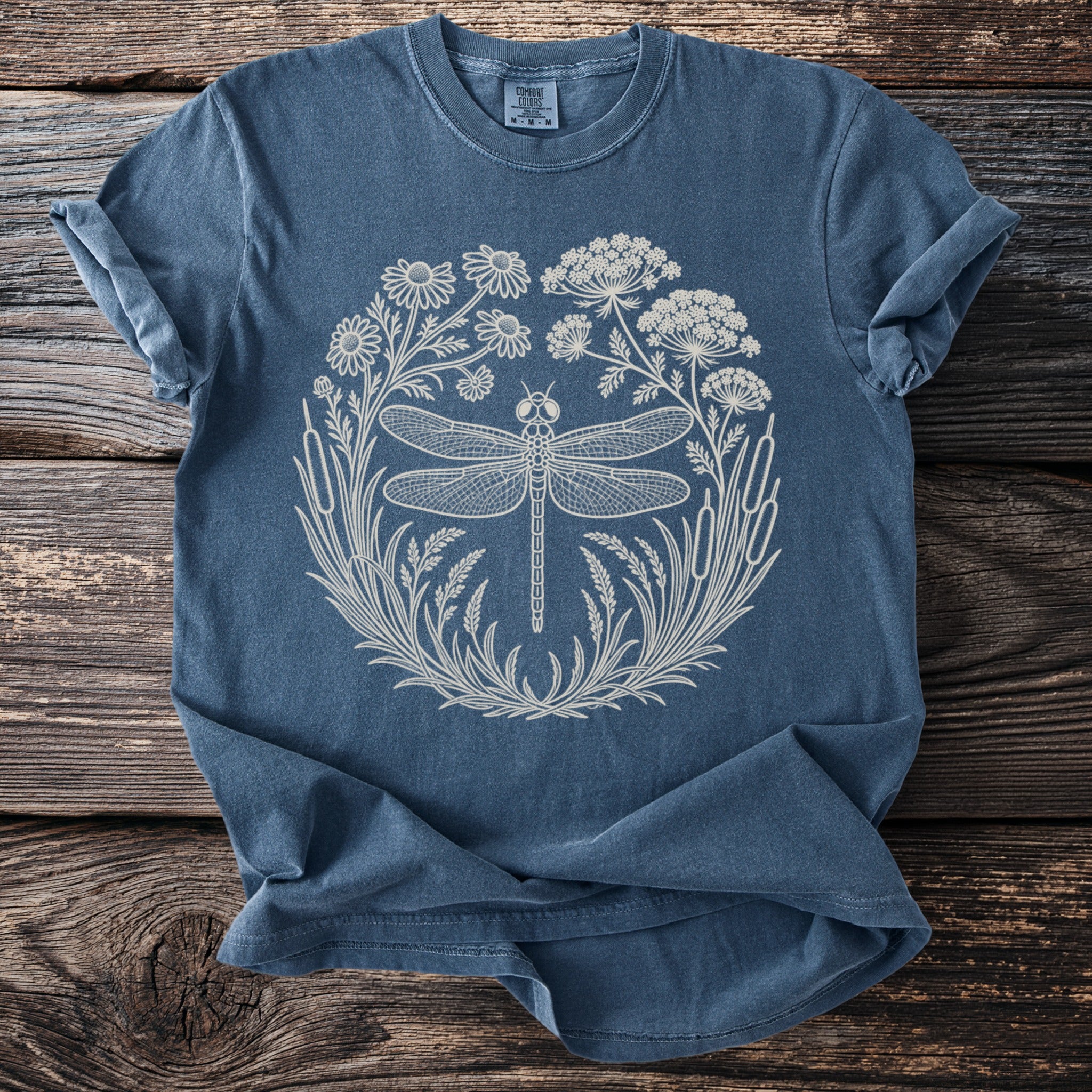 Blue t-shirt with cream dragonfly and floral circular graphic.