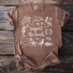 Brown t-shirt with white graphic of marine animals and text "respect the locals."