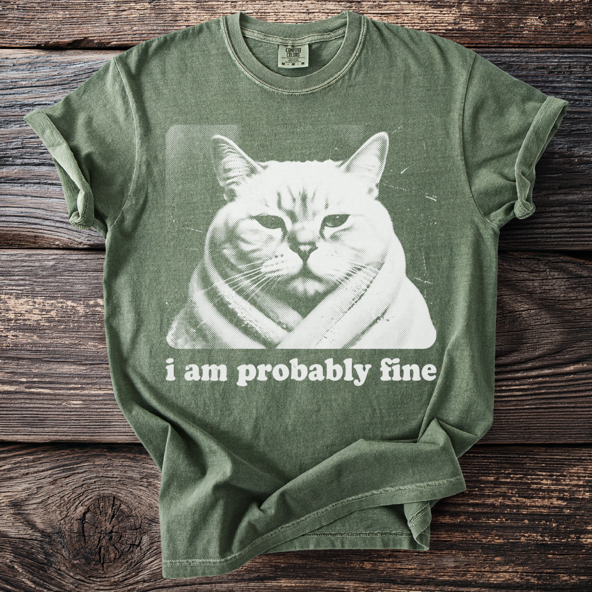 Green t-shirt with a white graphic of a cat wrapped in a blanket and text that reads "I am probably fine."