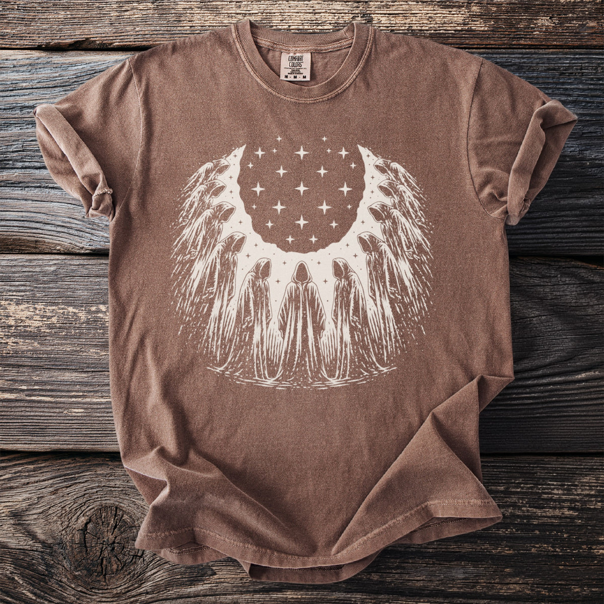 Brown t-shirt with white graphic of cloaked figures surrounding a star-filled moon.