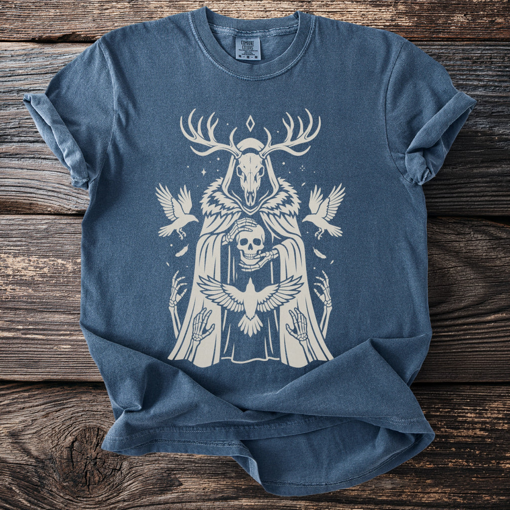 Blue t-shirt with a beige graphic of a skeletal figure wearing antlers and holding a skull.
