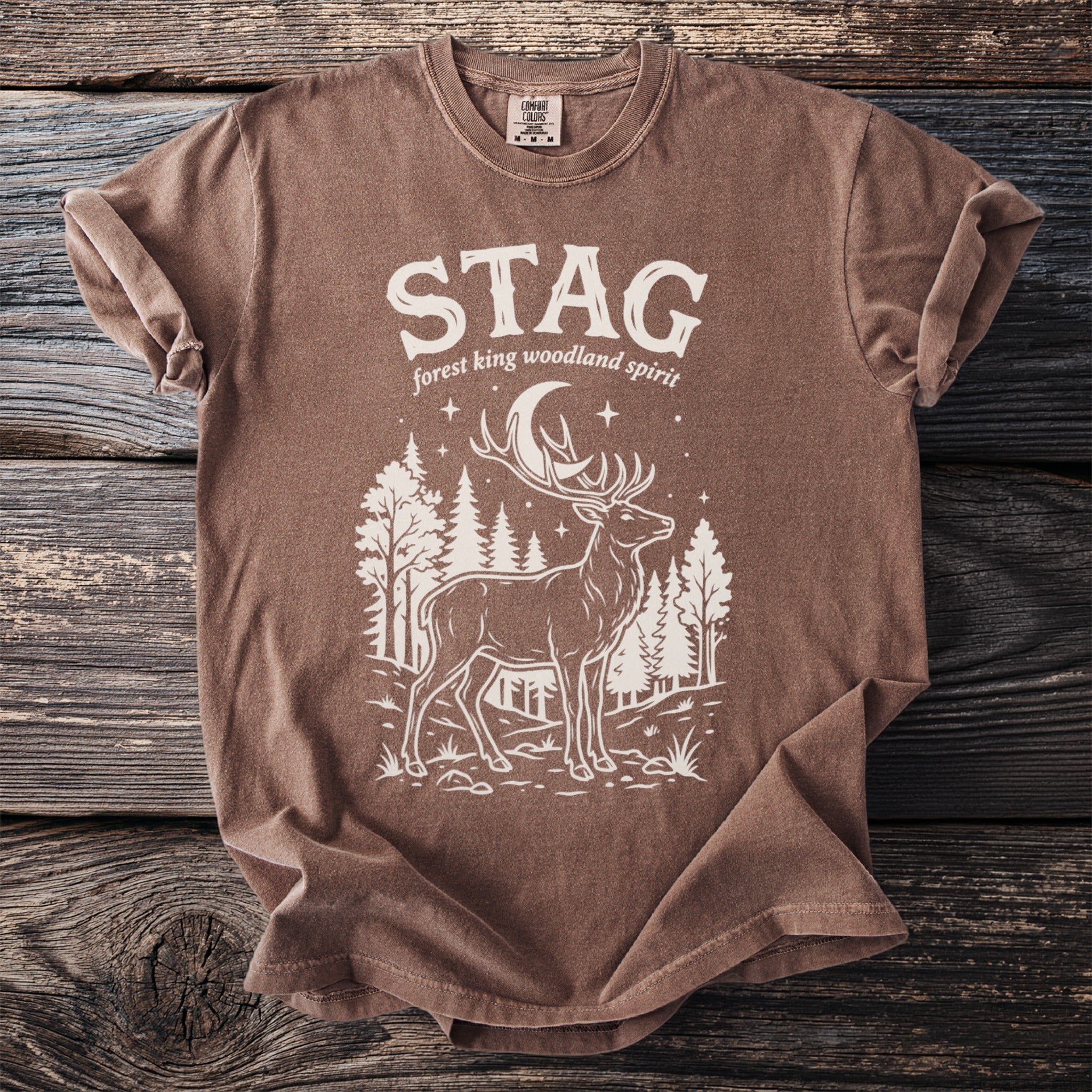 Brown t-shirt with white stag, forest, moon, and "STAG forest king woodland spirit" text.