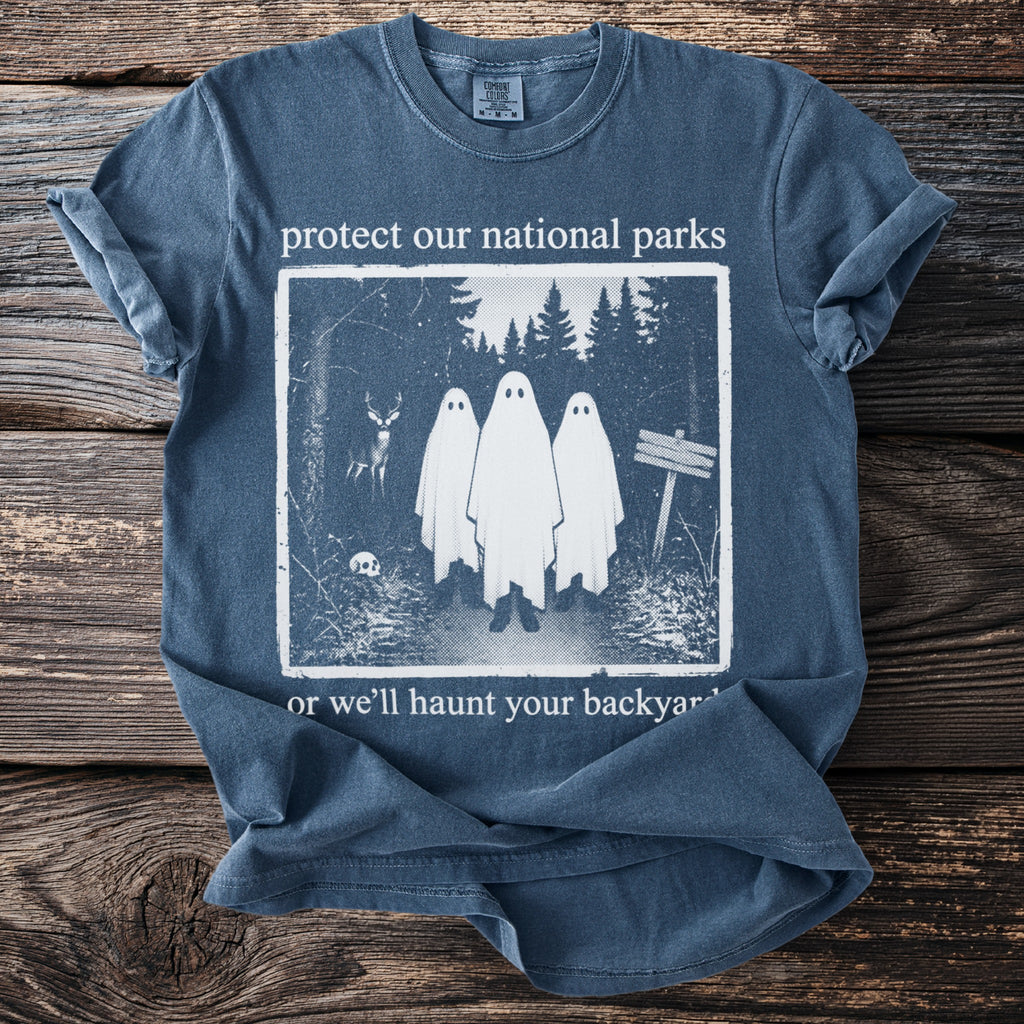 Blue t-shirt with ghosts, deer, skull, and trees. Text reads "protect our national parks or we'll haunt your backyard."