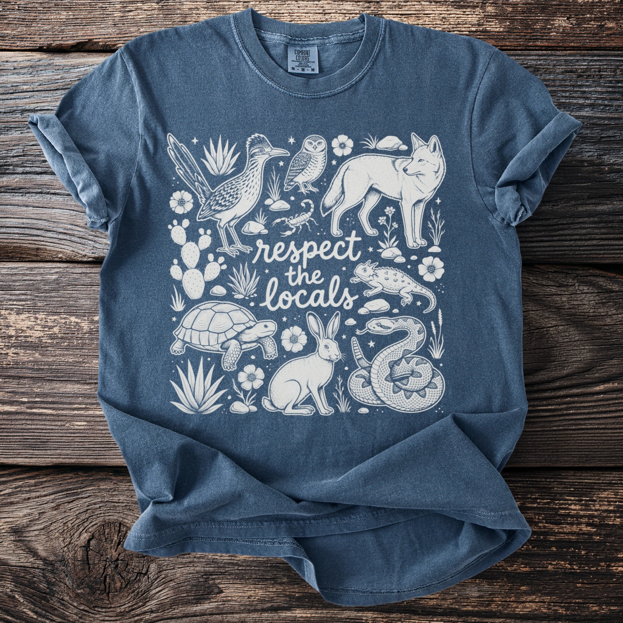 Blue t-shirt with a white line drawing of desert animals and "respect the locals" text.