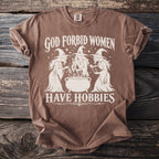 Brown t-shirt with white graphic text "God Forbid Women Have Hobbies" and three witches.