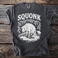 Dark gray t-shirt with white text "SQUONK" above a weeping dog with dripping tears and body.