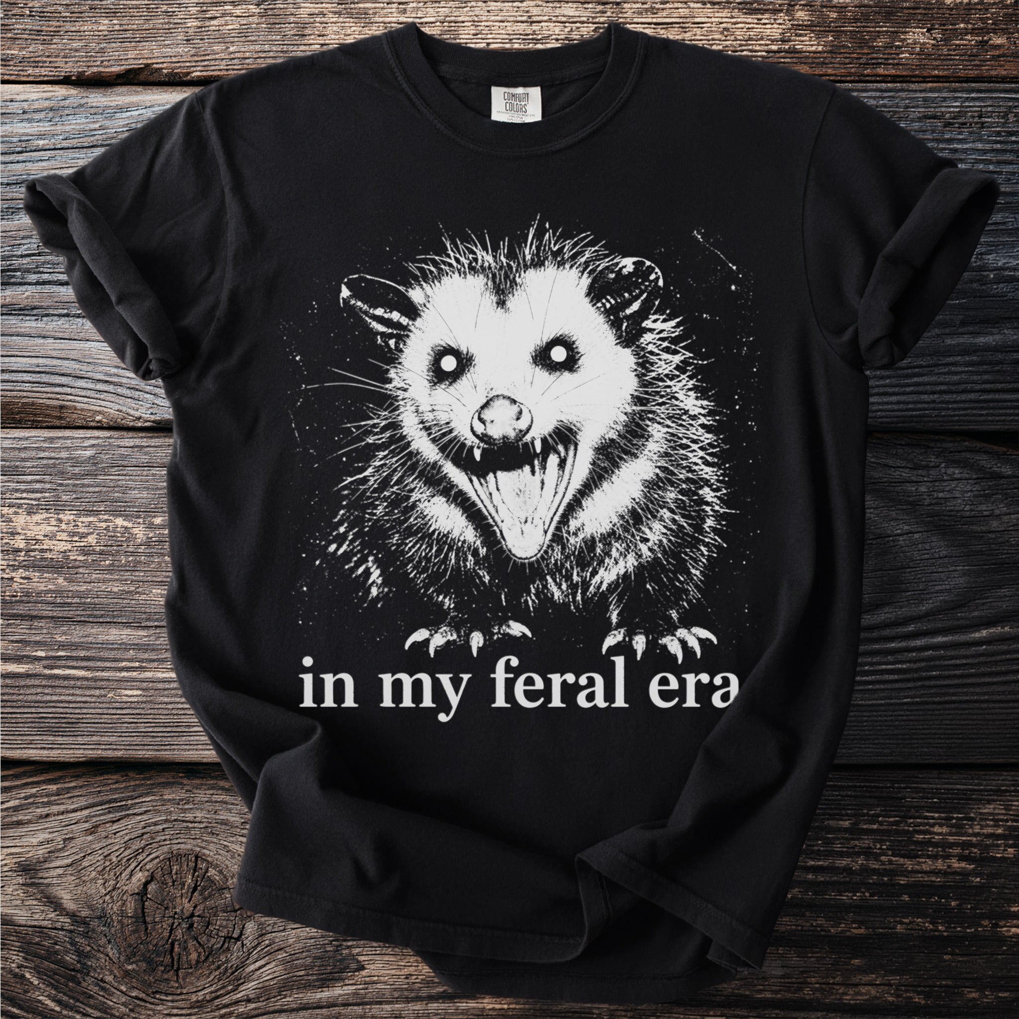 Black t-shirt with a white graphic of a screaming opossum and text "in my feral era".