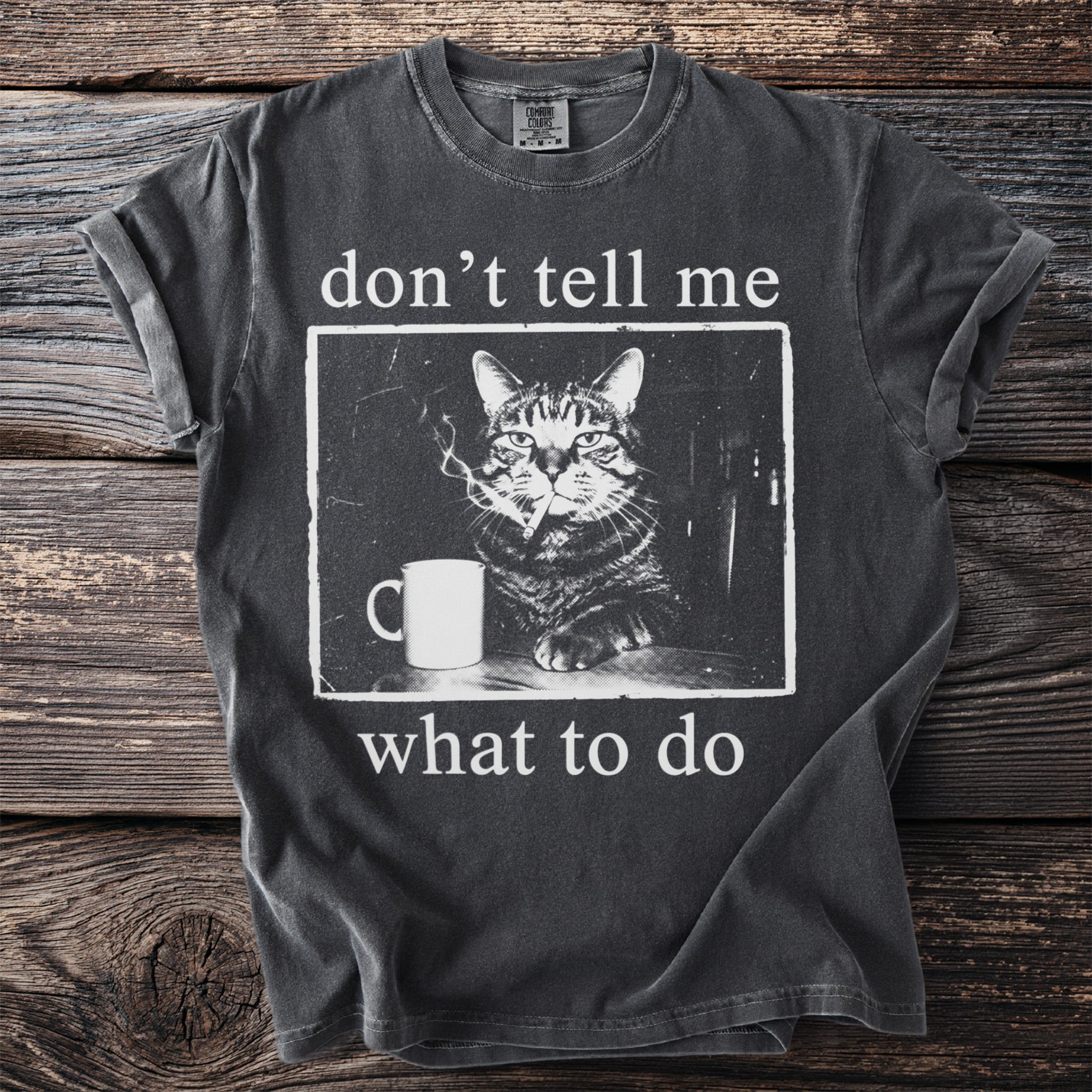 T-shirt graphic of a cat smoking a cigarette next to a mug with text.