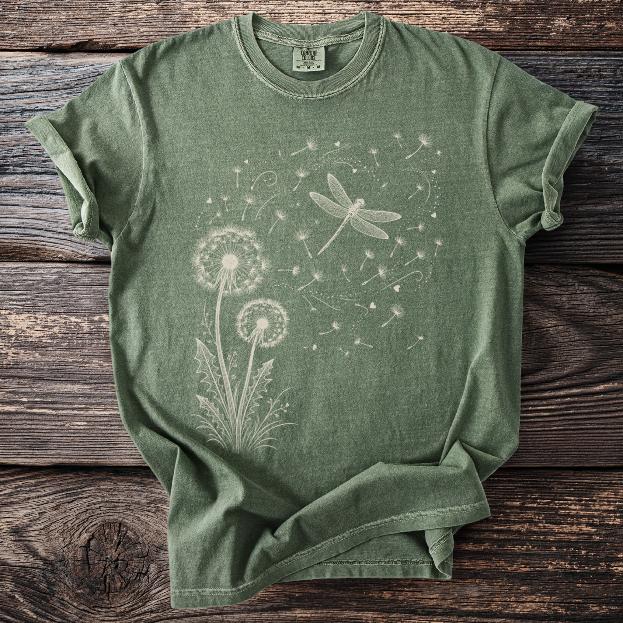 Green t-shirt with a line drawing of dandelions and a dragonfly.