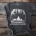 Dark gray t-shirt with a graphic of two ravens and text "attempted murder".