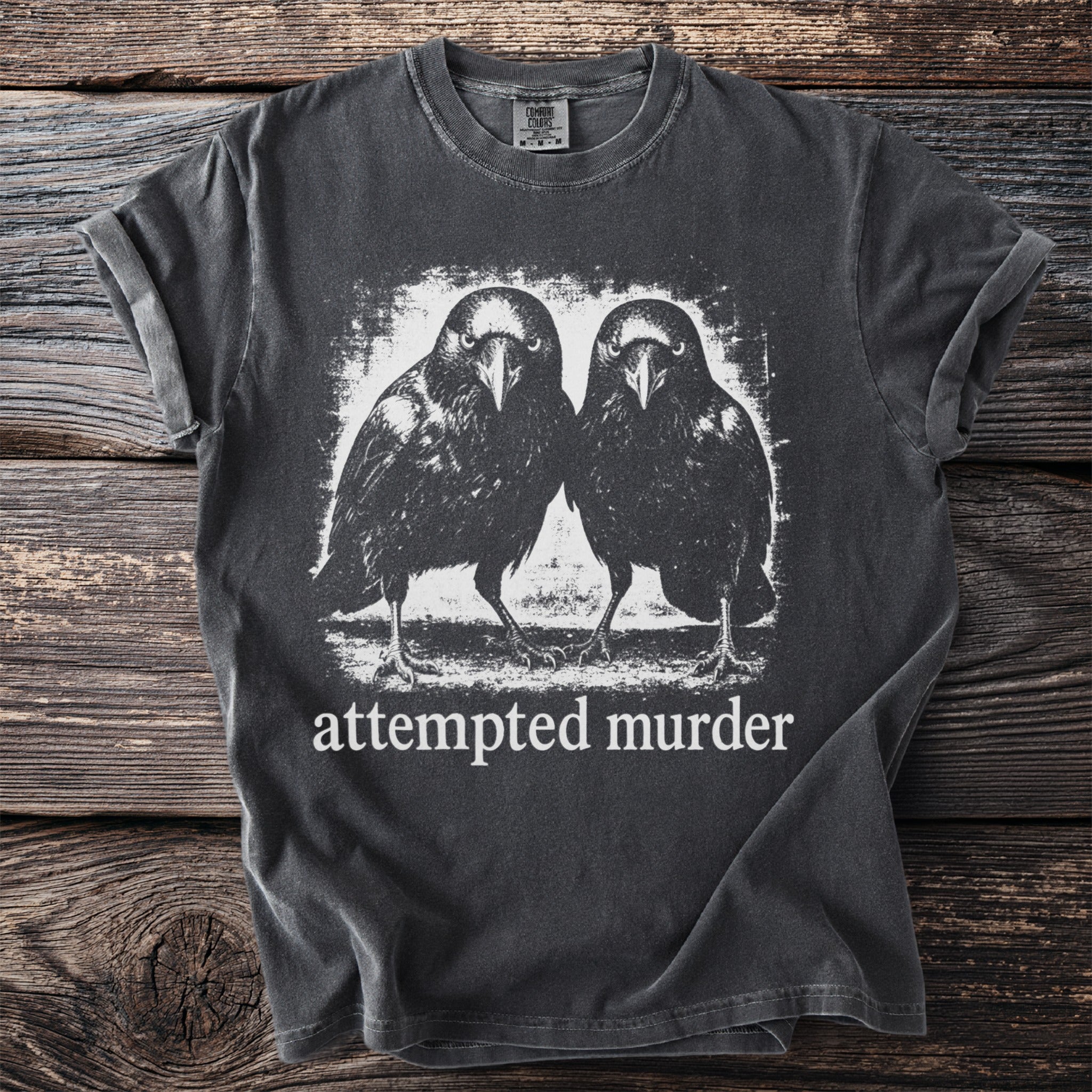 Dark gray t-shirt with a graphic of two ravens and text "attempted murder".
