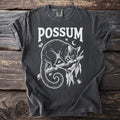Dark grey t-shirt with white graphic of a possum on a branch, text "POSSUM".