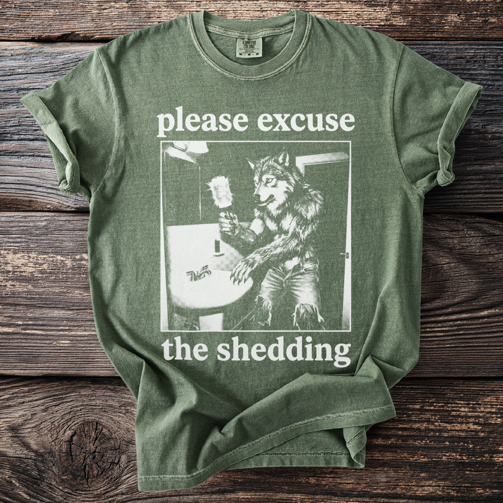 Green t-shirt with wolf illustration and text "please excuse the shedding".