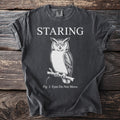 Charcoal t-shirt with "STARING" text above an owl illustration and "Fig. 1: Eyes Do Not Move."