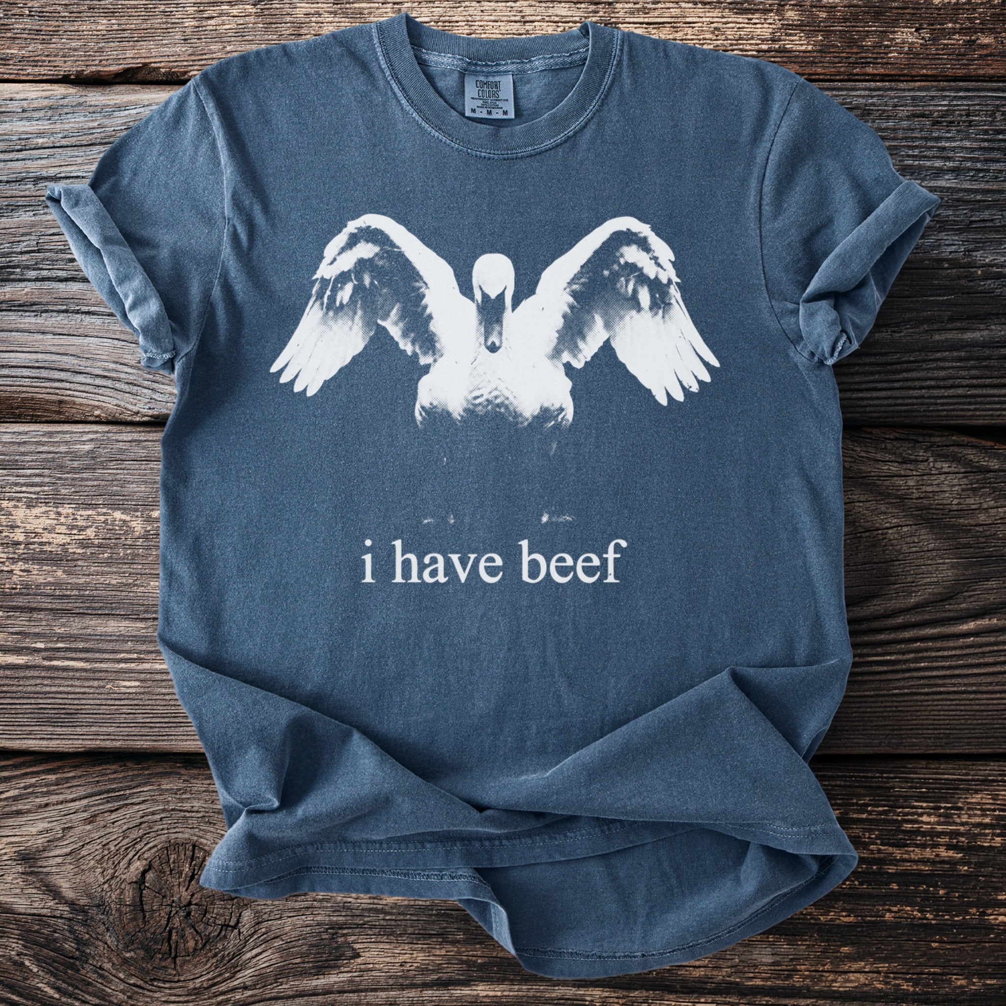 Blue t-shirt with a graphic of a swan with wings spread and "i have beef" text.