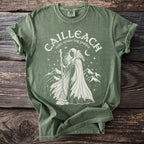 Green t-shirt with a cream graphic depicting the "Cailleach, Celtic winter hag goddess".