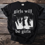 Black t-shirt with white text "girls will be girls" and witch silhouettes.