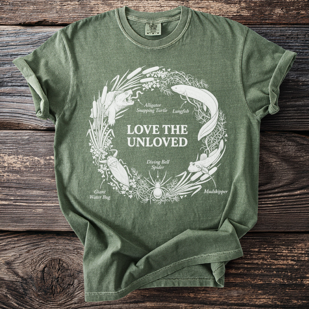 Green t-shirt with white circular graphic of "love the unloved" and various aquatic animals.