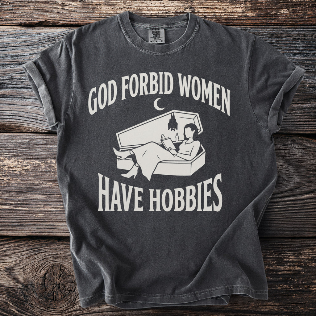 Dark grey t-shirt with white text "GOD FORBID WOMEN" and a coffin graphic with a person reading.