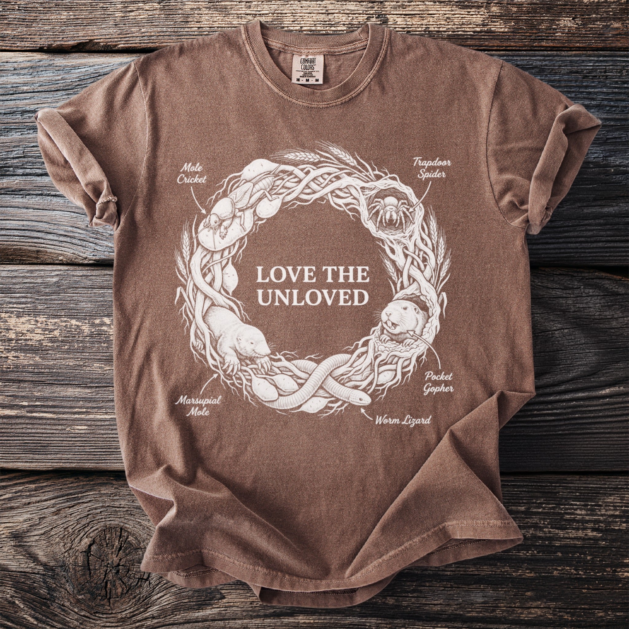 Brown t-shirt with white graphic of "LOVE THE UNLOVED" and various creatures in a circular design.