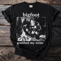 Bigfoot holding sausage on a fork by campfire with text "grabbed my wein(er)".