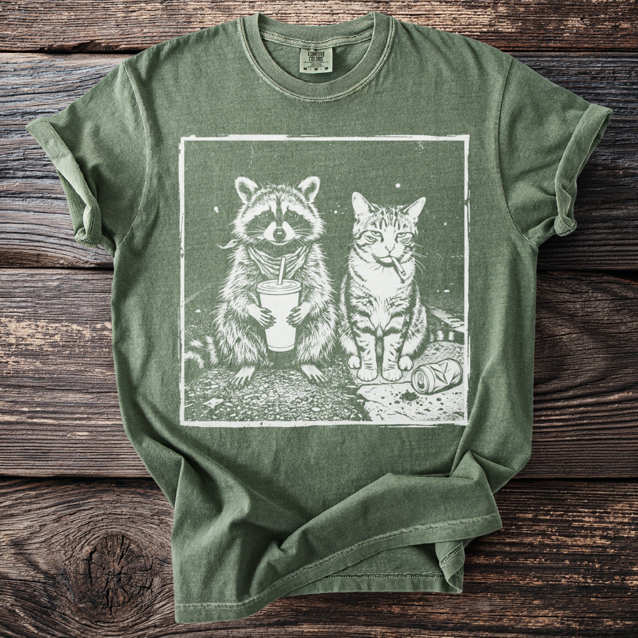 Green t-shirt featuring white graphic of raccoon with drink and cat smoking