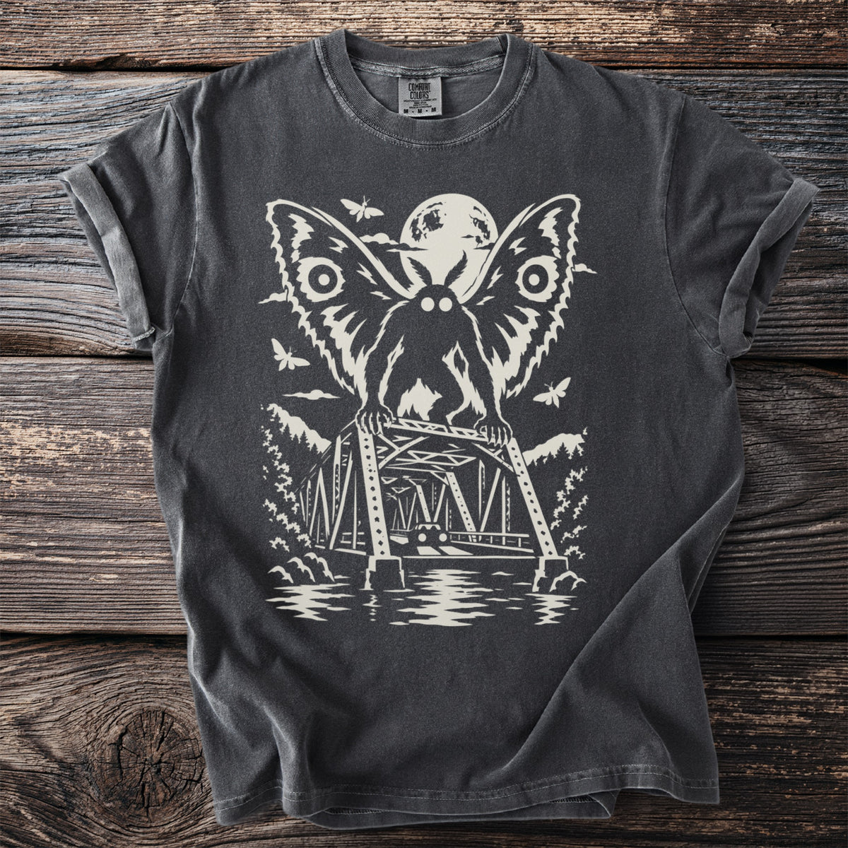 Charcoal t-shirt with a cream graphic of Mothman perched on a bridge under a full moon, with moths in the sky.
