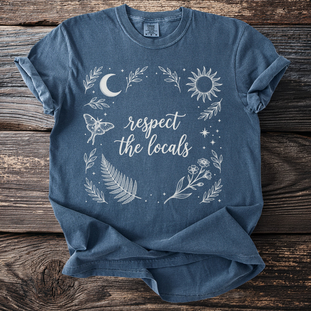 Blue t-shirt with white celestial and floral design and text "respect the locals".