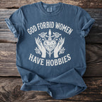 Blue t-shirt with white text "GOD FORBID WOMEN HAVE HOBBIES" and gothic graphic.