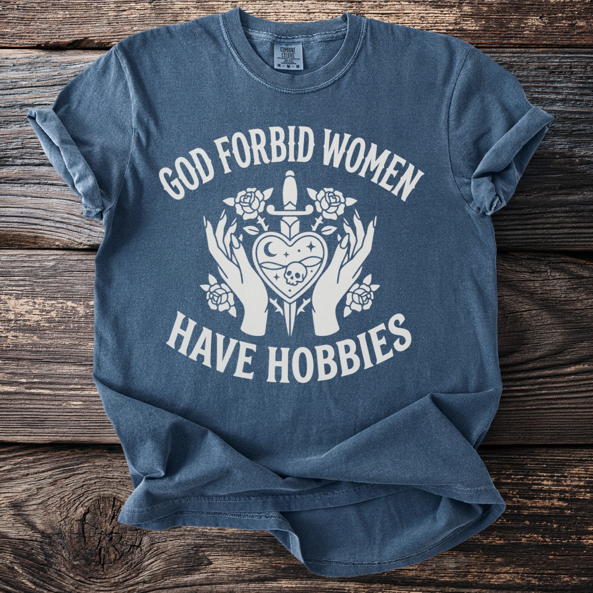 Blue t-shirt with white text "GOD FORBID WOMEN HAVE HOBBIES" and gothic graphic.