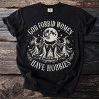 Black t-shirt with witches dancing around a bonfire under a full moon. Text reads "God forbid women have hobbies".