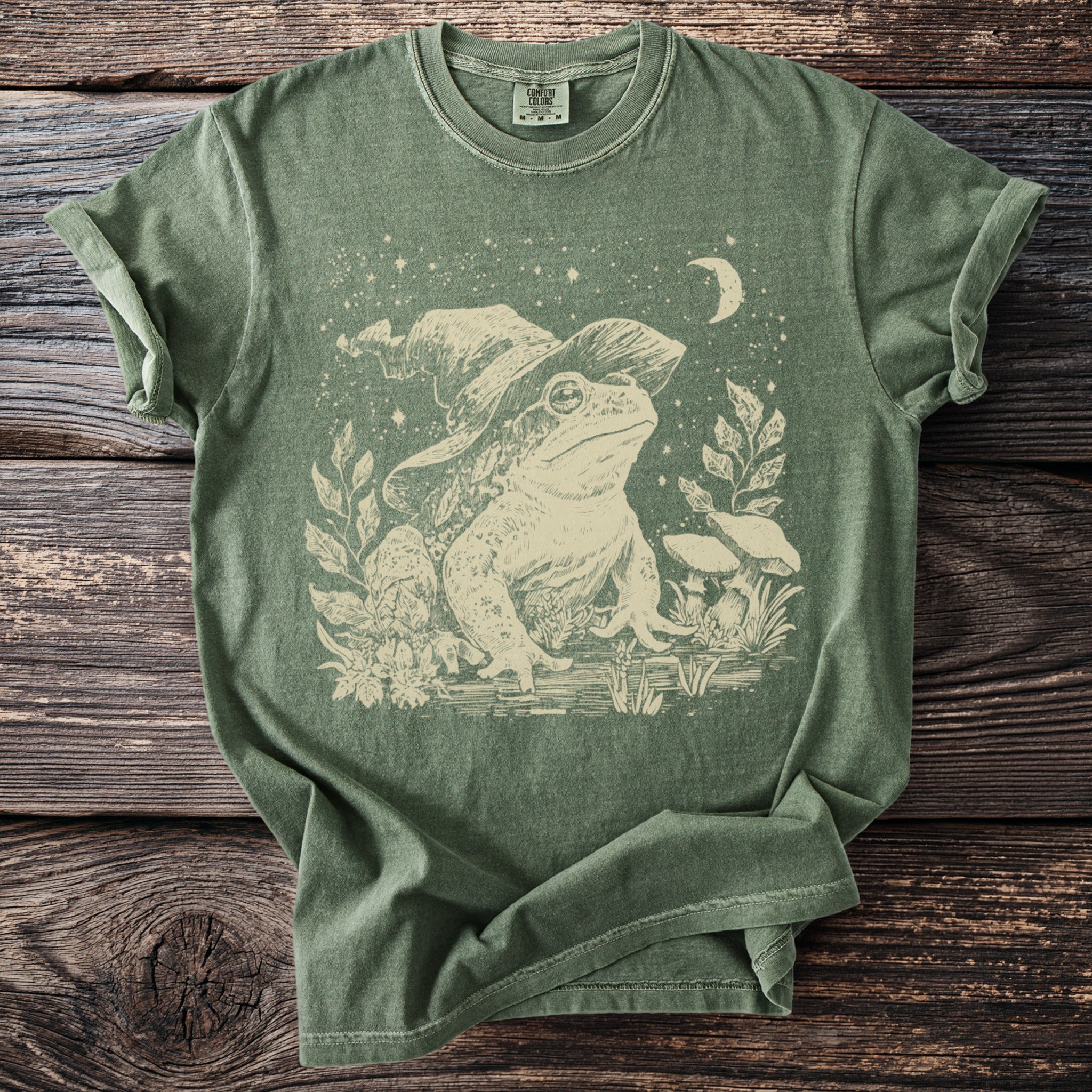 Green t-shirt with vintage frog wearing a witch hat and crescent moon graphic.