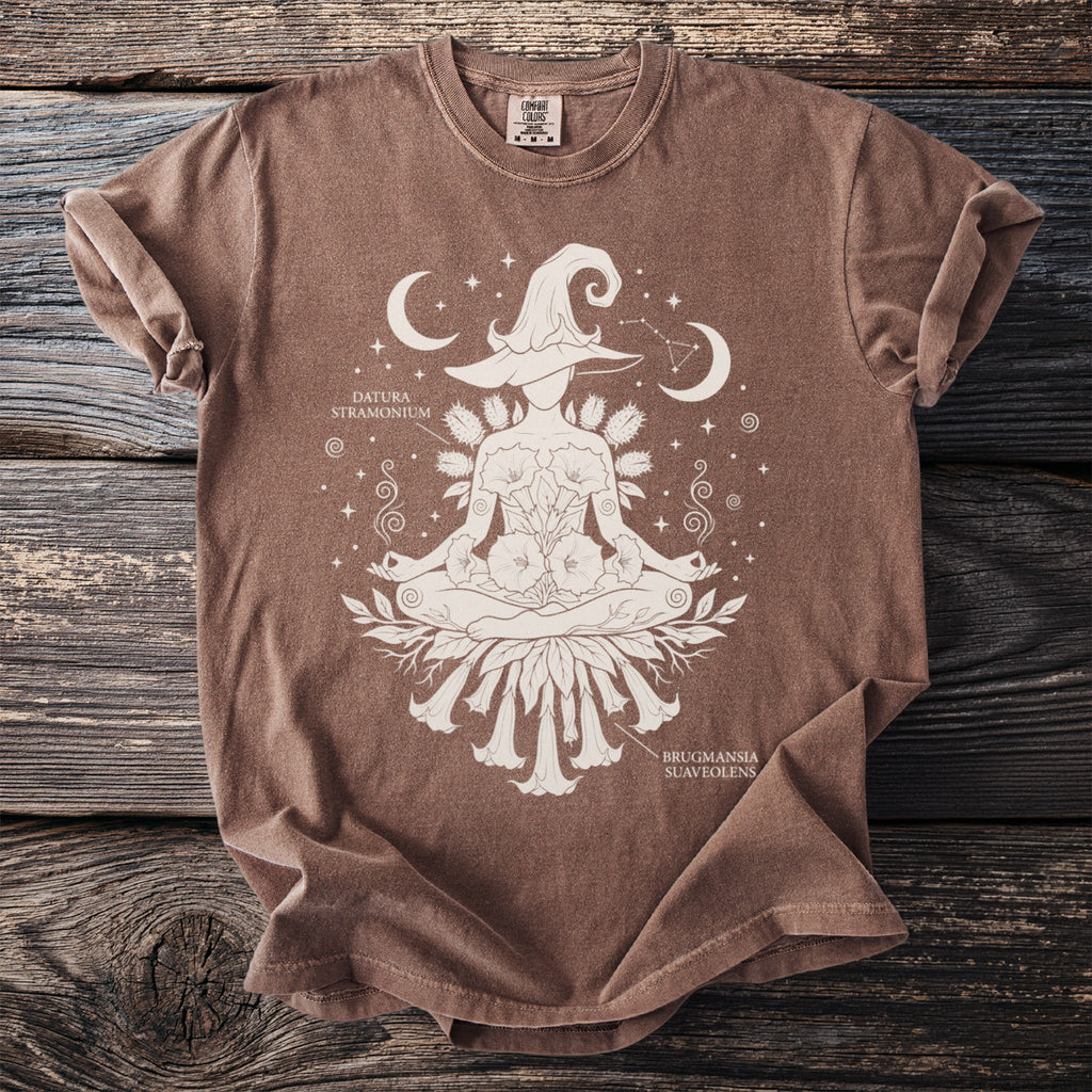 Brown t-shirt with white graphic of a meditating witch hat figure with datura and brugmansia.