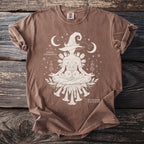 Brown t-shirt with white graphic of a meditating witch hat figure with datura and brugmansia.