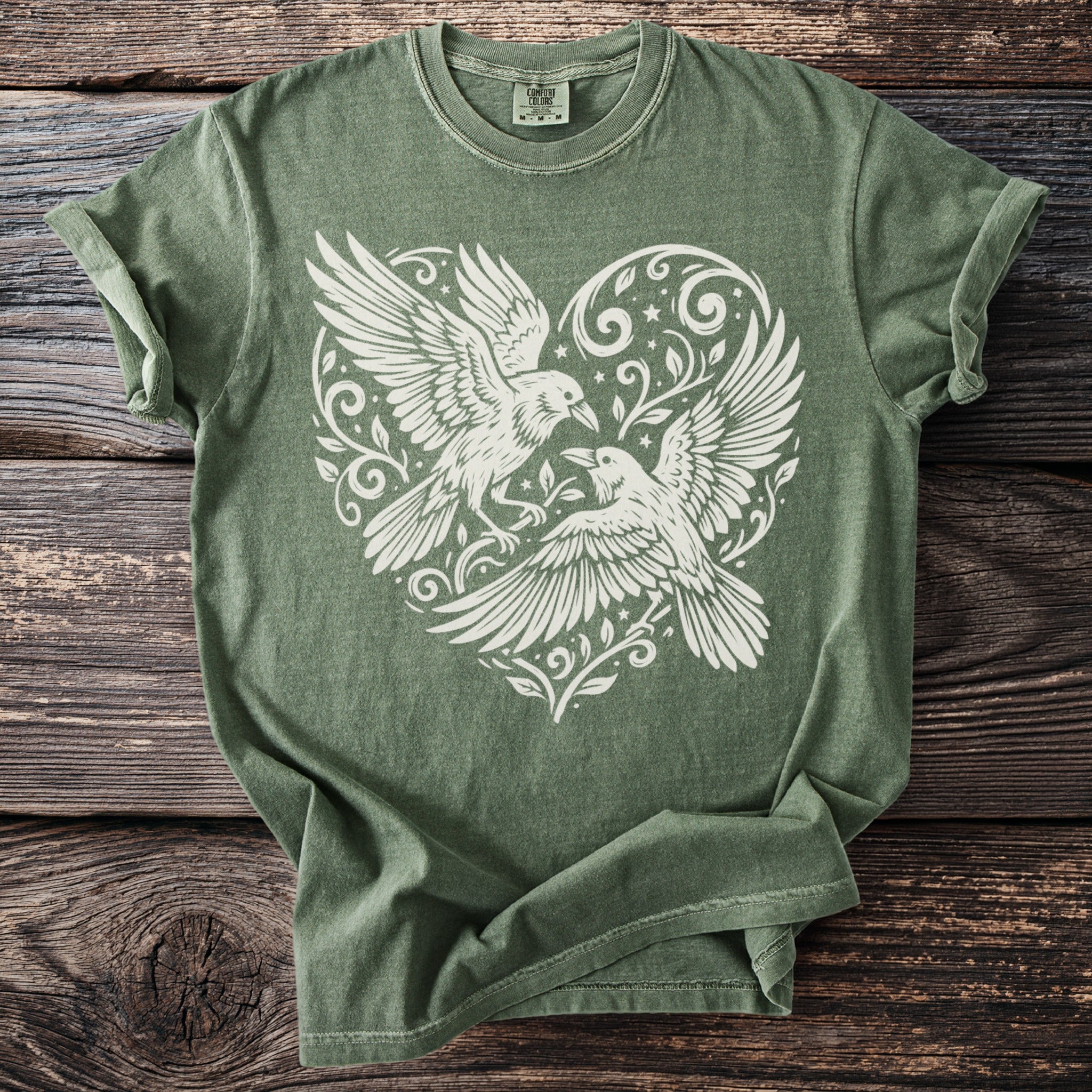 Green t-shirt with white print of two birds and a heart design.