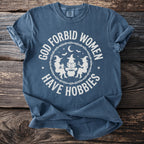Blue t-shirt with "God Forbid Women Have Hobbies" and witchy graphics.