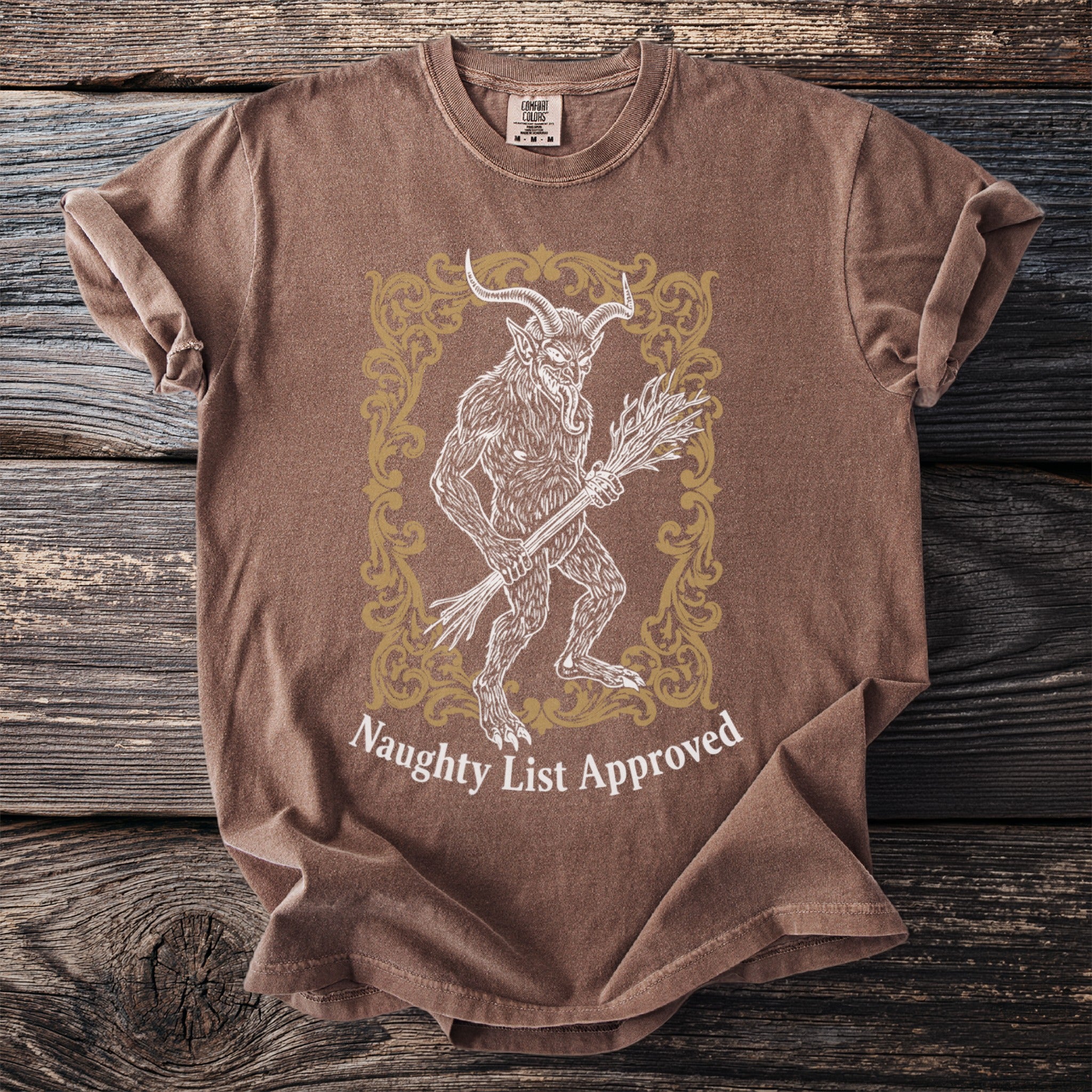 Brown t-shirt with a Krampus illustration and "Naughty List Approved" text.