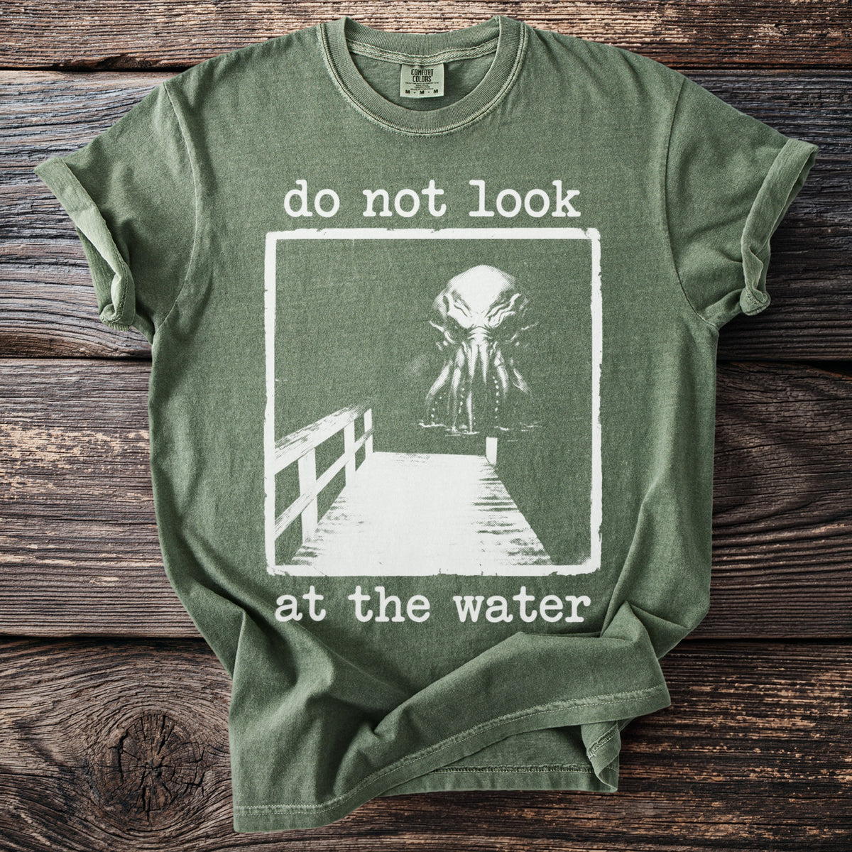 Green t-shirt with white text and an illustration of a monstrous head and tentacles.